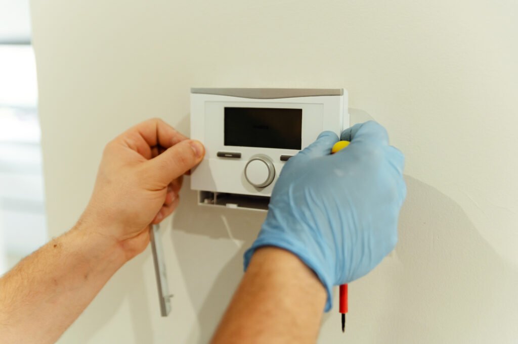 Technician adjusting a wall-mounted smart thermostat inside a Fort Lauderdale home